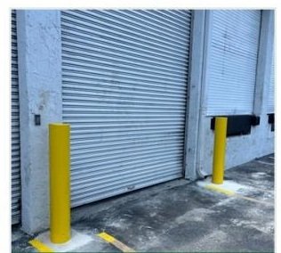 Completed yellow safety bollards at a loading door